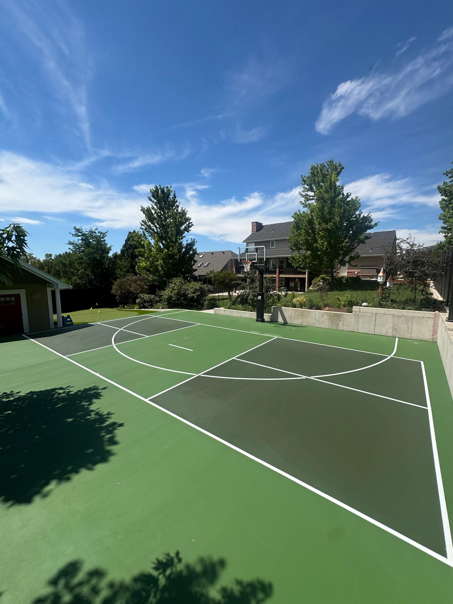Two-tone green multi-sport backyard court with white basketball and pickleball lines